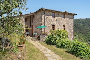 A stone building with a patio, outdoor seating, and a view of the surrounding landscape.