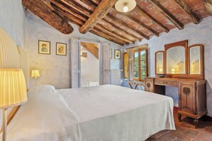 A bedroom with a bed, a wooden dresser, a mirror, and a lamp.