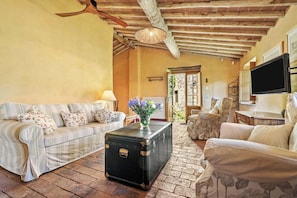A cozy living room with a sofa, armchair, and a vintage suitcase as a coffee table.