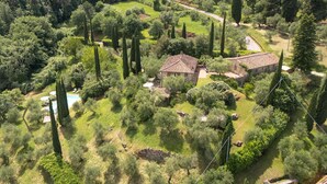 Una vista aerea di una proprietà rurale con due edifici in pietra, immersa nel verde e circondata da alberi alti.