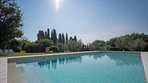 A rectangular swimming pool with clear blue water, surrounded by a well-maintained lawn and various trees. - Stunning private villa for 12 people with A/C, WIFI, private pool, TV and panoramic view (Orentano)