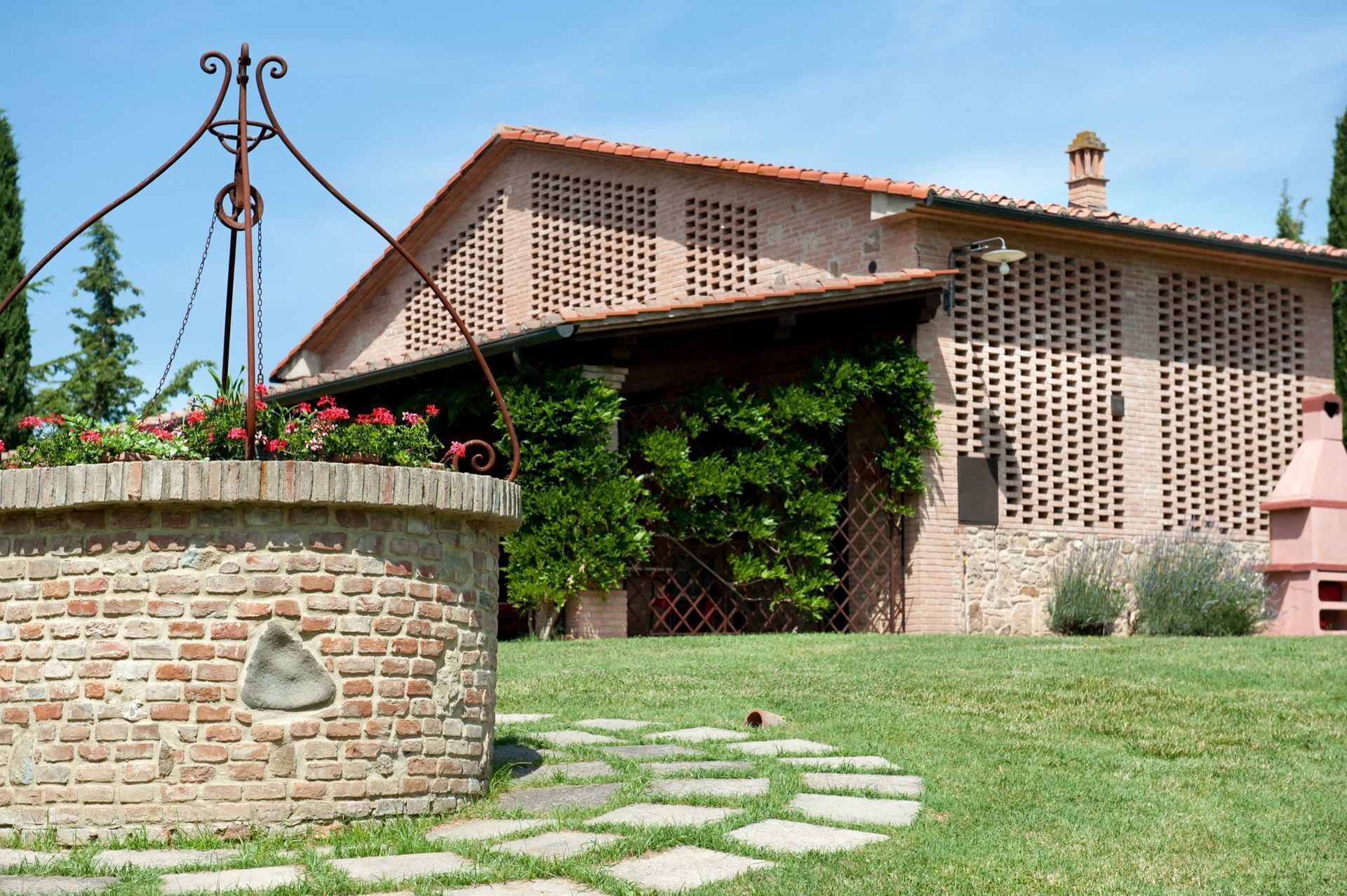 Una casa de ladrillo con techo de tejas, un sendero de piedra y una escultura de metal en primer plano.
