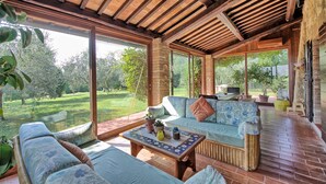 A covered patio with a wooden ceiling, large windows, and a seating area with a sofa and table. - Beautiful private villa for 7 guests with private pool, A/C, TV and panoramic view (Cetona)