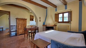 Un dormitorio con una cama grande, un escritorio de madera, una silla y una chimenea.