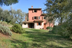 A two-story house with a red facade, a tiled roof, and a front entrance.