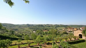 A rural landscape with terraced gardens, a stone building, and rolling hills in the background.