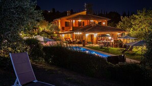A two-story house with a swimming pool, outdoor seating, and a well-lit patio area. - Villa with WIFI, A/C, pool, TV, patio, pets allowed, panoramic view, close to San Gimignano (Montaione)