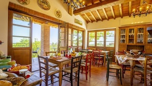 A rustic dining area with wooden furniture, large windows, and a view of greenery outside. - Villa with WIFI, A/C, pool, TV, patio, pets allowed, panoramic view, close to San Gimignano (Montaione)