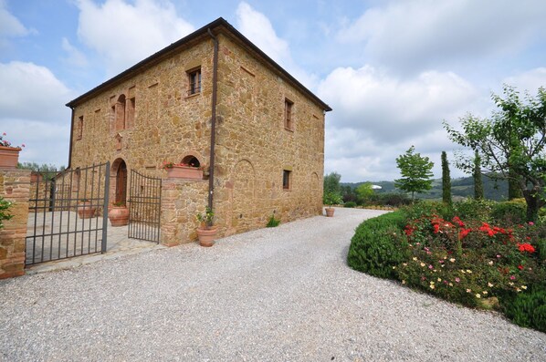 A stone building with a gravel driveway and a gated entrance.