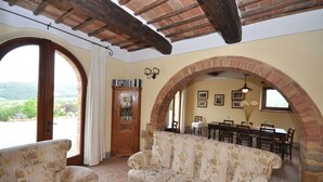 A cozy living room with a sofa, a wooden cabinet, and a dining area with a table and chairs. - Private Villa with A/C, private pool, WIFI, TV, pets allowed, panoramic view, close to Montepulciano (Montefollonico)