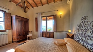 Quarto com cama grande, guarda-roupa de madeira e janela com vista.