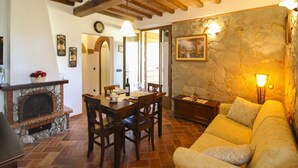 A cozy living room with a stone fireplace, wooden dining table, and a comfortable sofa. - Stunning private villa for 8 guests with A/C, WIFI, private pool and TV, close to Montepulciano (Sinalunga)