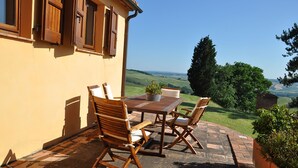 An outdoor patio with a table and chairs, a potted plant, and a view of the countryside. - Lovely apartment for 6 guests with pool, WIFI, TV, patio, pets allowed and panoramic view (Centeno)