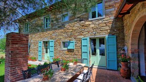 A stone building with a patio, outdoor seating, and potted plants.