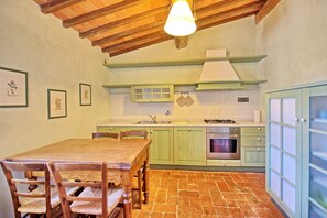 A kitchen with a wooden table and chairs, green cabinets, a stove, and a sink.