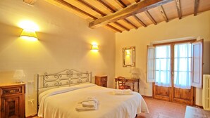 A bedroom with a bed, bedside tables, a mirror, a wooden door, and a window with curtains. - Nice apartment with pool, WIFI, TV, pets allowed and panoramic view, close to Greve In Chianti (Le Quattro Strade)