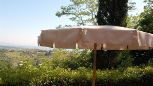 Een buiten eethoek met een tafel, stoelen en een parasol.