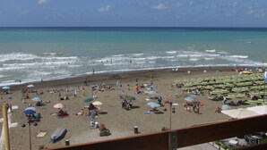 Una playa con sombrillas, tumbonas y gente disfrutando del agua.