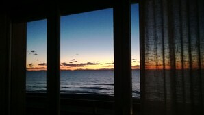 Vista a través de persianas de un atardecer sobre el océano.
