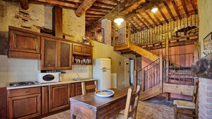 Una cocina rústica con armarios de madera, una mesa de comedor y una escalera que lleva a un nivel superior.