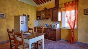 Une cuisine avec des meubles de rangement en bois, un réfrigérateur blanc, un four à micro-ondes et une table à manger avec des chaises.
