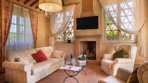 A cozy living room with a fireplace, a sofa, a chair, and a coffee table. - Beautiful private villa for 6 guests with private pool, A/C, WIFI, TV and veranda, close to Lucca (Capannori)