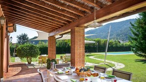 An outdoor dining area with brick pillars, a white table set for breakfast, and a view of a pool and mountains in the background. - Beautiful private villa for 6 guests with private pool, A/C, WIFI, TV and veranda, close to Lucca (Capannori)
