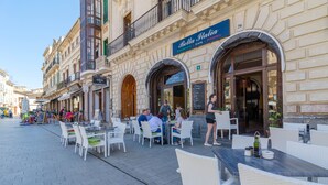 An outdoor cafe with tables and chairs, a sign for Bella Italia, and people dining. - CAN FOSQUET - Beautiful traditional villa with private pool. Free WiFi. (Llucmajor)