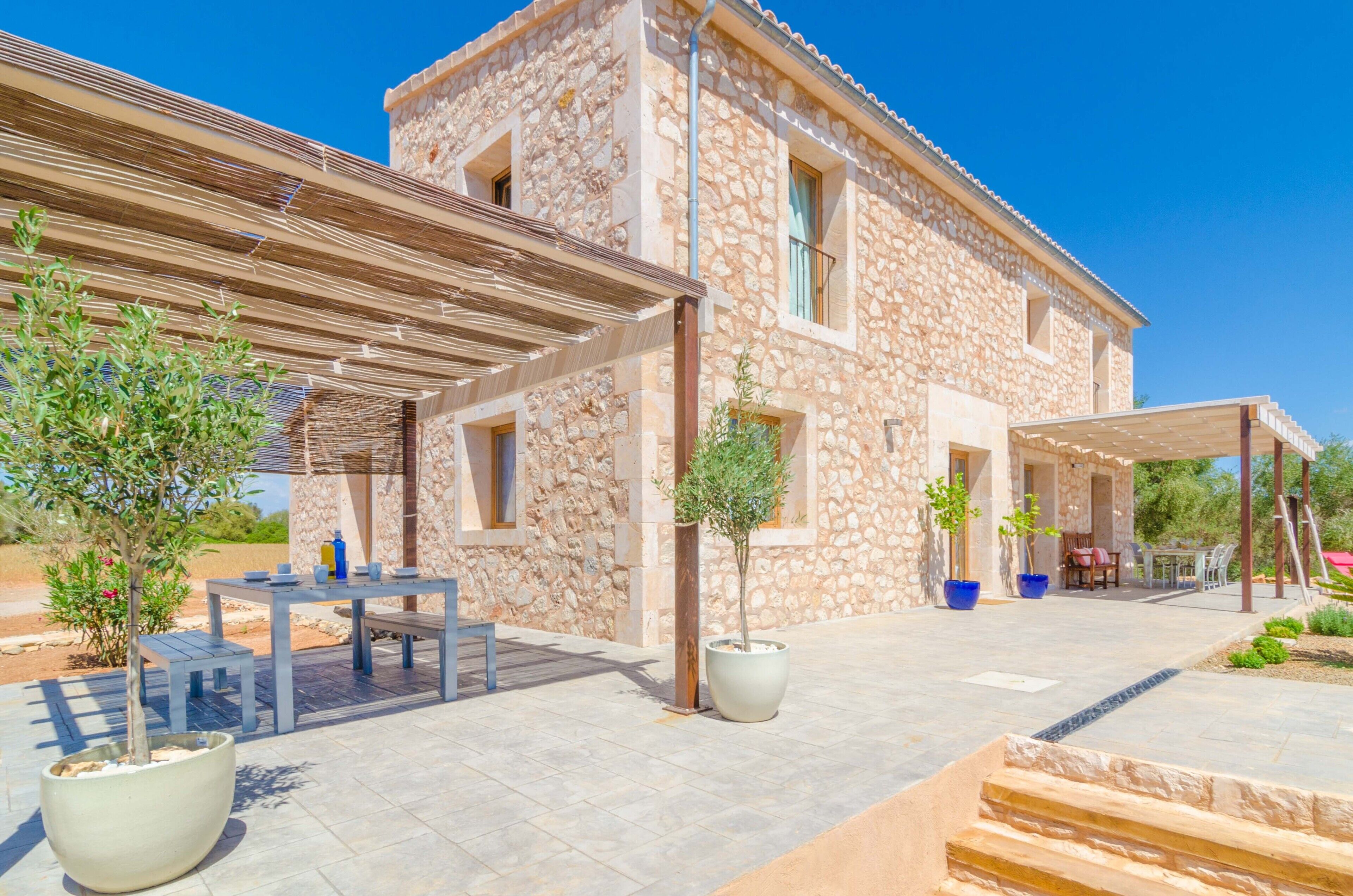 A stone building with a covered patio, outdoor seating, and potted plants.