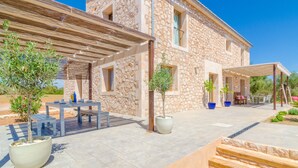 A stone building with a covered patio, outdoor seating, and potted plants.