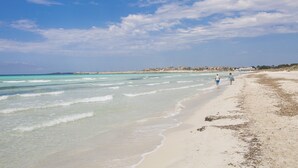 A beach with clear turquoise waters and a sandy shore.