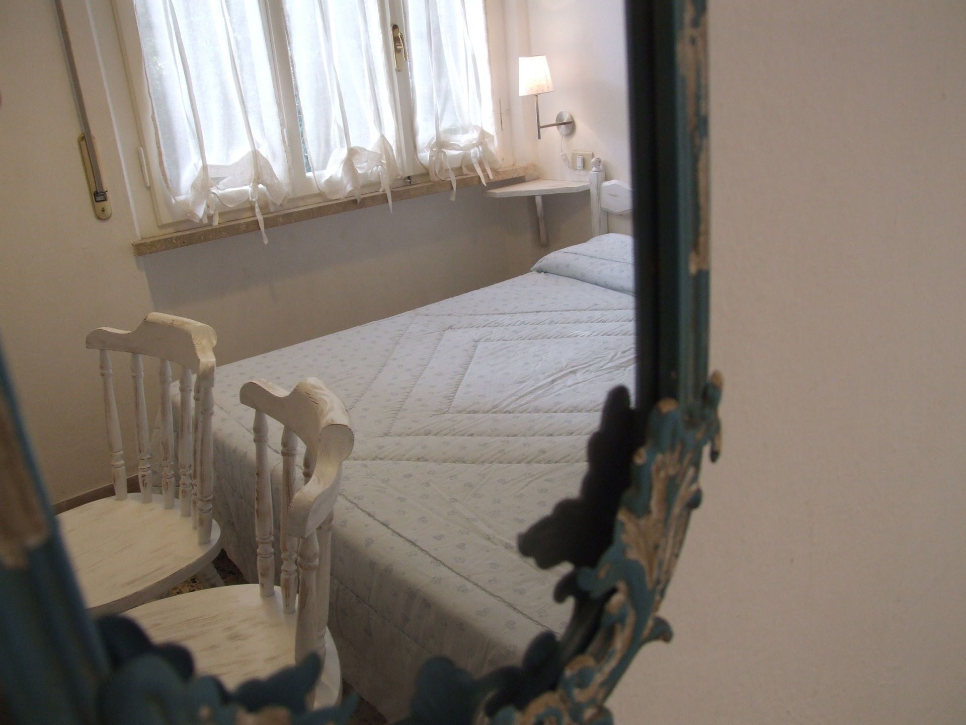 A bedroom with a bed, a chair, a nightstand, and a mirror.