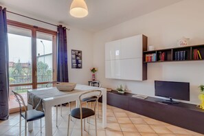 Eine moderne Küche mit Esstisch, Stühlen, einem Fernseher und einem Bücherregal.