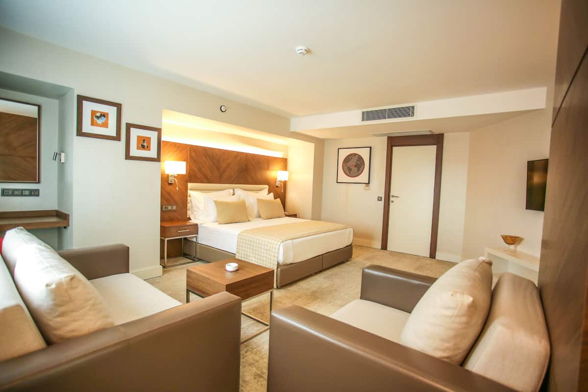 A hotel room with a bed, two sofas, a coffee table, and a desk.