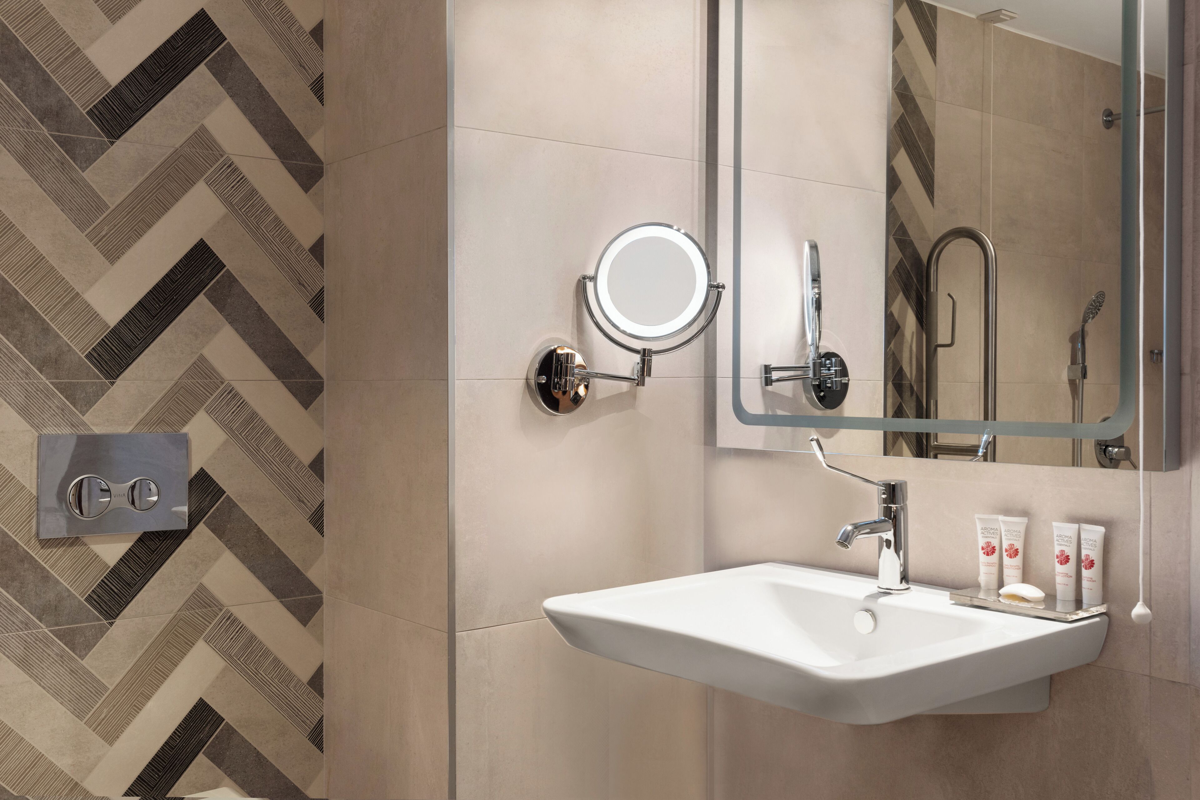 A modern bathroom with a white sink, a round mirror, and a shower area.