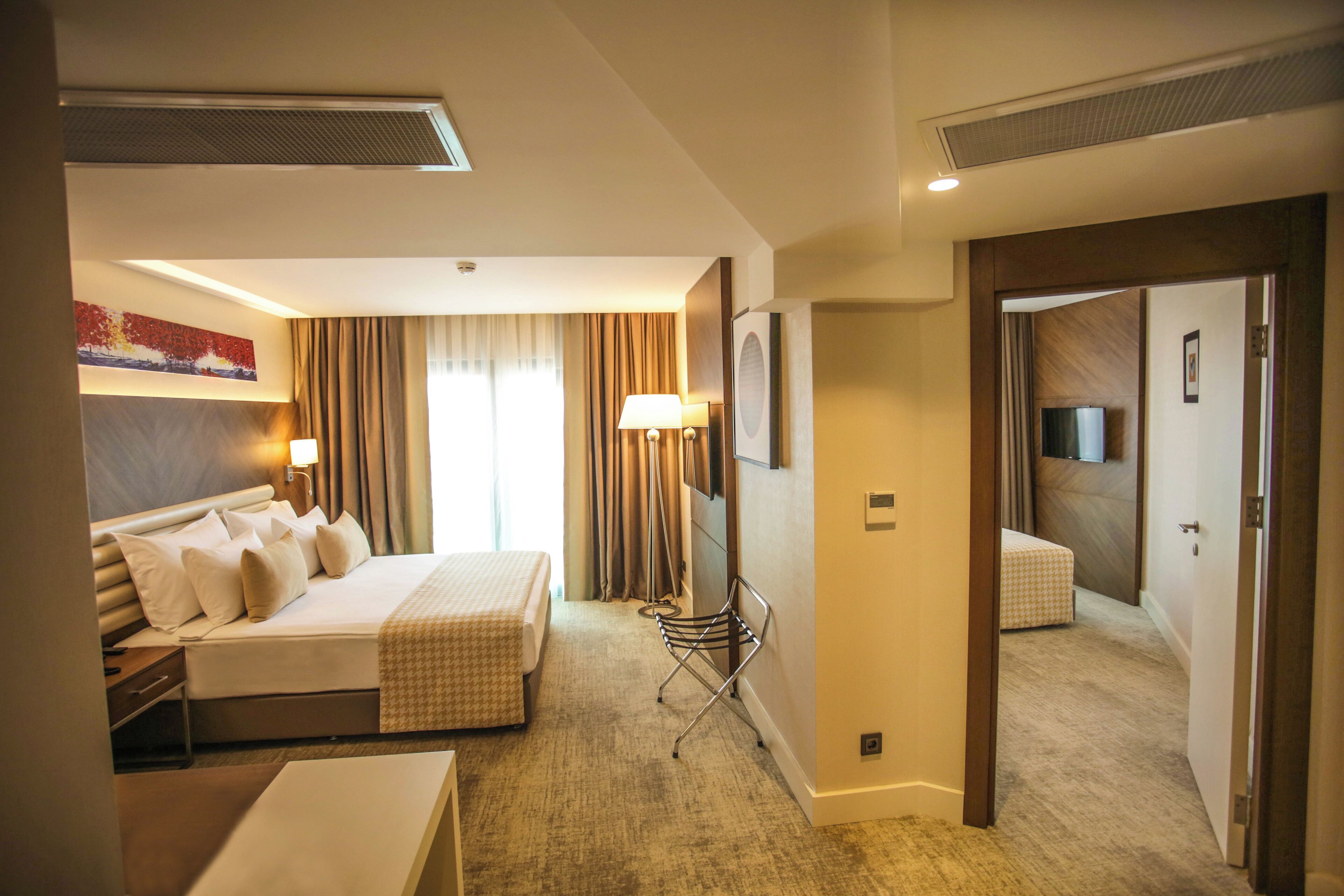Une chambre d’hôtel avec un grand lit, des tables de chevet, un bureau, une chaise, une télévision et une armoire.