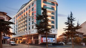 Un hotel de varios pisos con un llamativo letrero 'RAMAD', que presenta un diseño moderno con grandes ventanales y una fachada curva.
