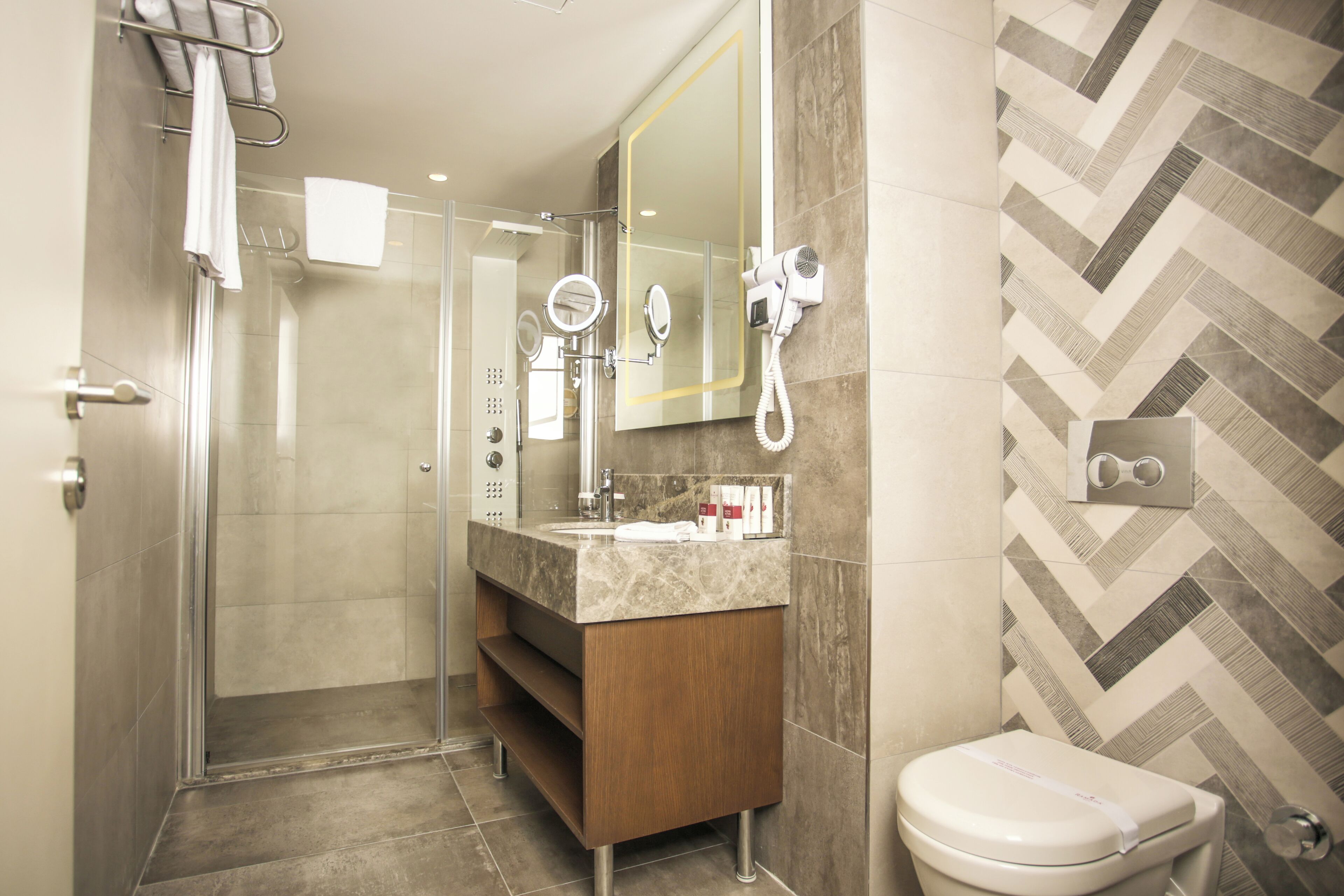 Un baño moderno con cabina de ducha de vidrio, tocador de mármol y inodoro.