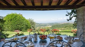 Ein Tisch ist für ein Frühstück gedeckt, mit Blick auf Hügel und Weinberge.