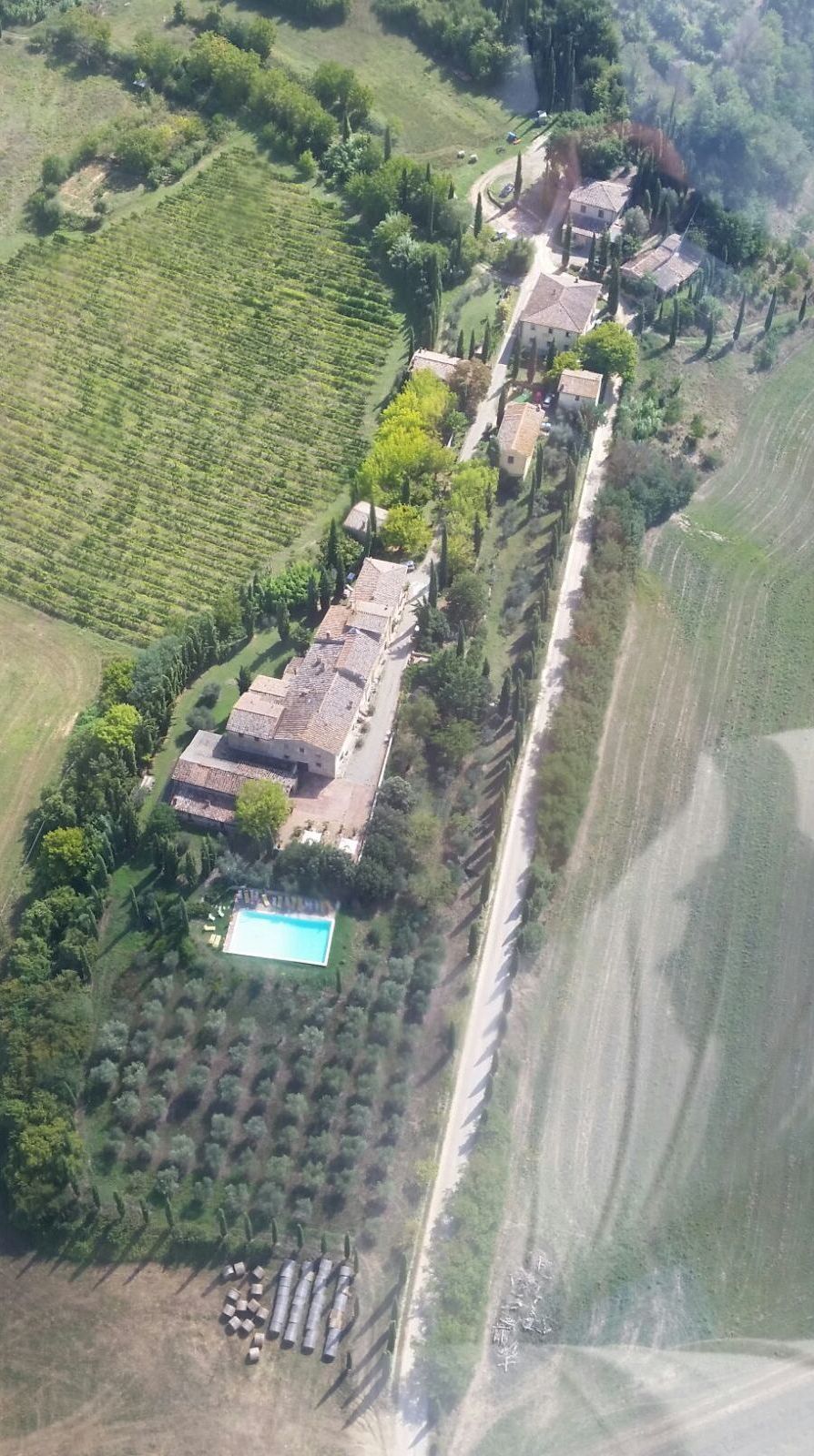 Vista aérea de una propiedad con piscina, terrazas de cultivo y una hilera de edificios.