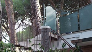 Eine Treppe mit Metallgeländer, umgeben von Bäumen und einem grünen Zaun.