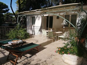 A covered outdoor seating area with a table and chairs, a sun lounger, and a potted plant. - Beautiful apartment for 4 people with WIFI, A/C, TV, patio and panoramic view (Marina Di Castagneto Carducci)