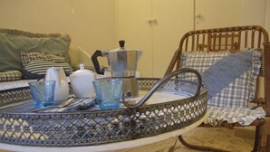 Une petite table ronde avec un plateau en métal, une cafetière et deux tasses en verre.