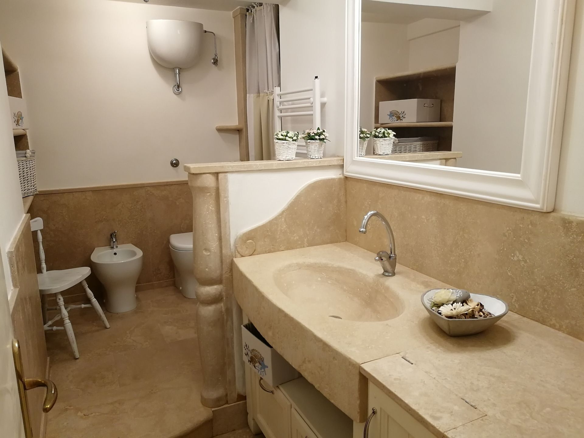 A bathroom with a beige sink, a bidet, a toilet, and a mirror.