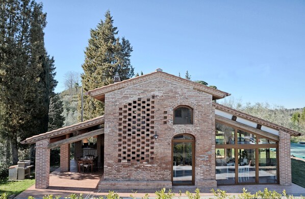 A modern house with a brick exterior, large windows, and a patio area. - Beautiful private villa for 6 guests with private pool, WIFI, A/C, TV and panoramic view (San Miniato)
