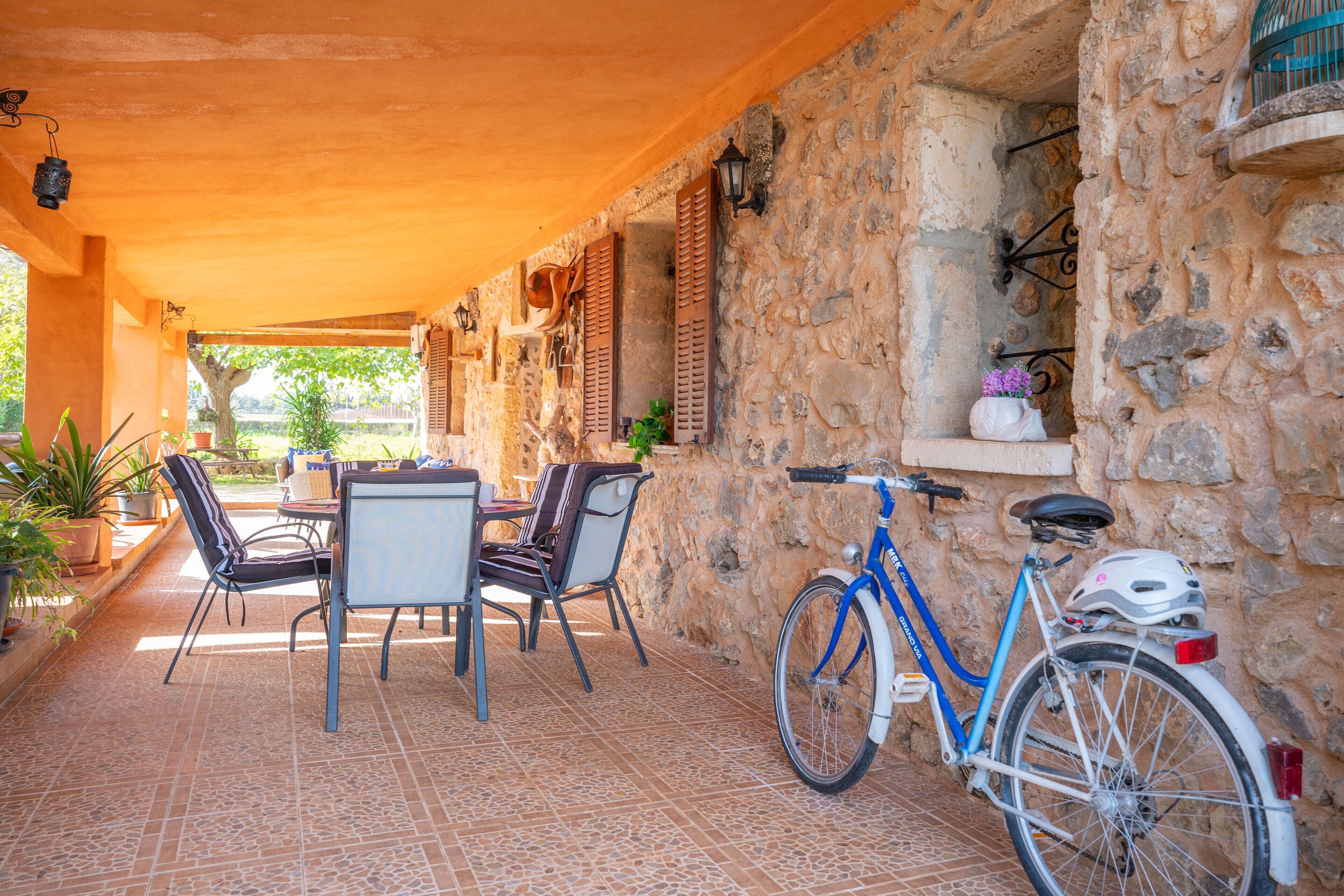 Un patio cubierto con paredes de piedra, una mesa con sillas y una bicicleta azul.