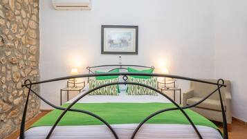 A bed with a metal frame, a green bedspread, and two bedside lamps. There is a framed picture on the wall above the bed.
