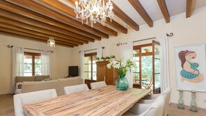 A dining area with a wooden table and white chairs, a chandelier, and a painting on the wall. - SA GARRIGA - Villa with private pool in INCA. Free WiFi (Inca)