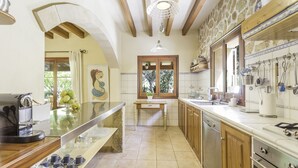 A kitchen with wooden cabinets, a built-in oven, a coffee machine, and a window with a view of greenery. - SA GARRIGA - Villa with private pool in INCA. Free WiFi (Inca)