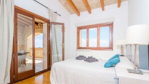 Een slaapkamer met een bed, een raam, een lamp en uitzicht op de omgeving.